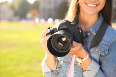 Young female photographer holding professional camera on street. Space for text