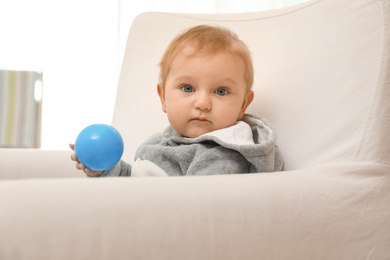 Photo of Cute little baby with blue ball in armchair