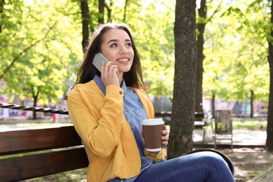 Young woman talking by phone outdoors on sunny day