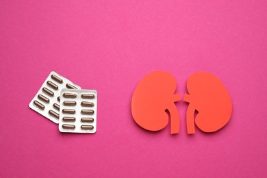 Paper cutout of kidneys and pills on magenta background, flat lay