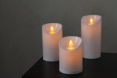 Glowing decorative LED candles on black table
