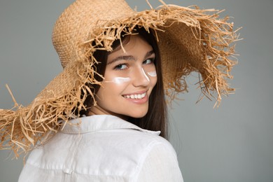 Photo of Teenage girl with sun protection cream on her face against grey background