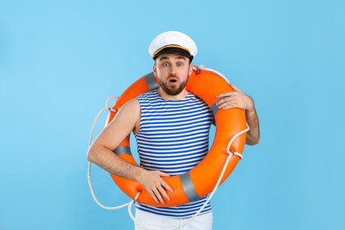 Surprised sailor with ring buoy on light blue background