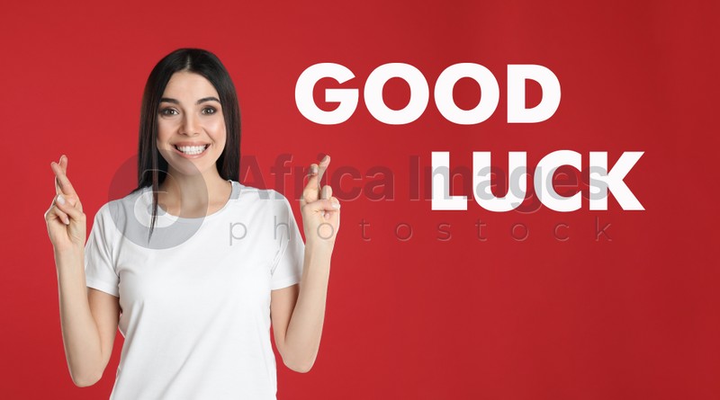 Image of Woman with crossed fingers on red background. Good luck superstition
