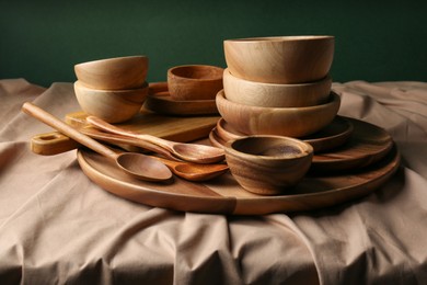 Photo of Set of wooden dishware and utensils on table against green background