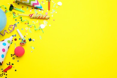 Photo of Flat lay composition with party hats and other festive items on yellow background, space for text. Birthday surprise