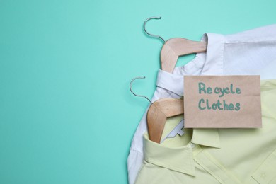 Photo of Recycling concept. Clothes and card with phrase on turquoise background, flat lay. Space for text