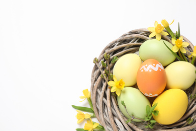 Colorful Easter eggs in decorative nest on white background, top view