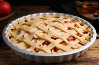 Raw traditional English apple pie in baking dish on wooden table, closeup