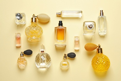Flat lay composition with different perfume bottles on light yellow background