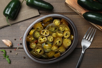 Photo of Fresh and pickled green jalapeno peppers on wooden table, flat lay