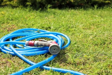 Photo of Watering hose with sprinkler on green grass outdoors, space for text