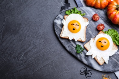 Halloween themed breakfast served on black table, flat lay and space for text. Tasty toasts with fried eggs in shape of ghost
