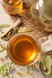 Freshly brewed tea, honey and dried herbs on white wooden table, flat lay