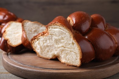 Cut homemade braided bread on wooden table, closeup. Traditional Shabbat challah