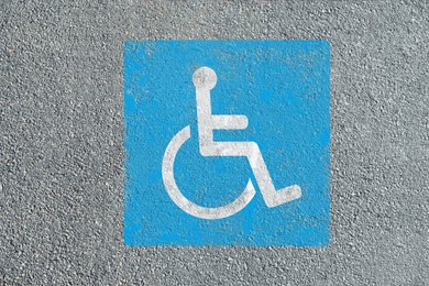 Wheelchair symbol on asphalt road, top view. Disabled parking permit