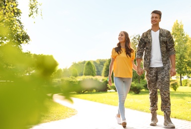 Man in military uniform walking with his girlfriend at sunny park