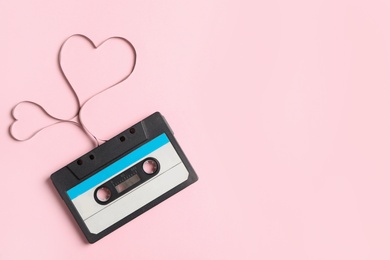 Top view of music cassette and hearts made with tape on pink background, space for text. Listening love song