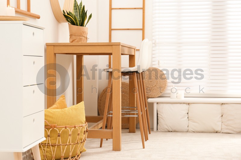 Photo of Stylish room interior with wooden table and bar stools