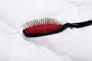 Photo of Cushion brush with fallen hair on white blanket