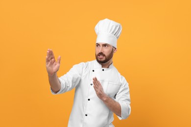 Photo of Emotional mature male chef on orange background
