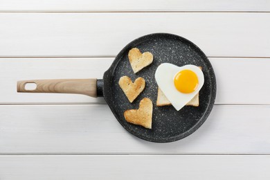 Photo of Romantic breakfast with heart shaped fried egg and toasts in pan on white wooden table, top view