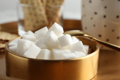 Refined sugar cubes in bowl on table, closeup