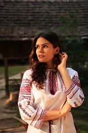 Photo of Beautiful woman wearing embroidered shirt in village. Ukrainian national clothes