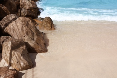 Beautiful sandy beach with rocks on sunny day
