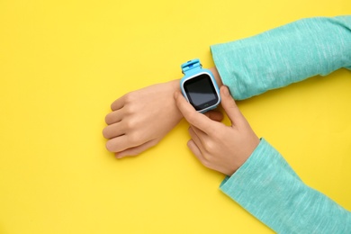 Boy with stylish smart watch on yellow background, top view