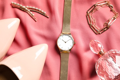 Flat lay composition with luxury wrist watch on pink fabric