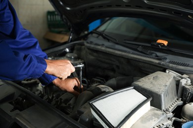 Photo of Professional mechanic fixing modern car at automobile repair shop, closeup