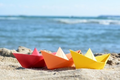 Photo of Three paper boats near sea on sunny day