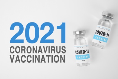 Vials with coronavirus vaccine on white background, flat lay 