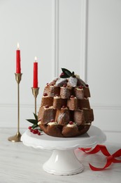 Photo of Delicious Pandoro Christmas tree cake with powdered sugar and berries near festive decor on white table