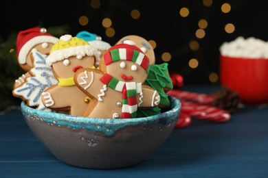 Delicious homemade Christmas cookies in bowl on blue wooden table against blurred festive lights. Space for text