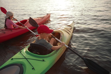 Children kayaking on river at sunset. Summer camp activity