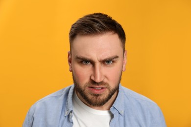 Angry young man on yellow background. Hate concept