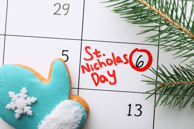 Gingerbread cookie and fir tree branch on calendar page with marked date, top view. December, 6 - Saint Nicholas Day
