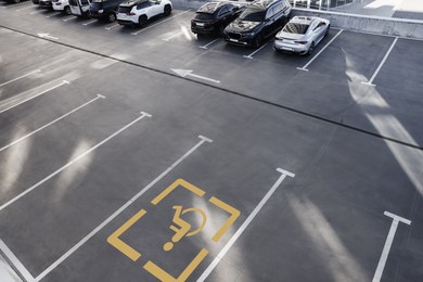 Image of Car parking lot with white marking lines and wheelchair symbol outdoors, above view