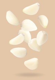 Image of Many garlic cloves falling on beige background