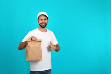 Young courier with paper bag on color background, space for text. Food delivery service