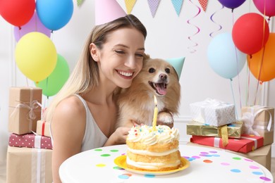 Happy woman celebrating her pet's birthday in decorated room