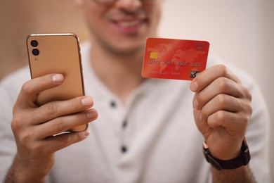 Man using smartphone and credit card for online payment, closeup