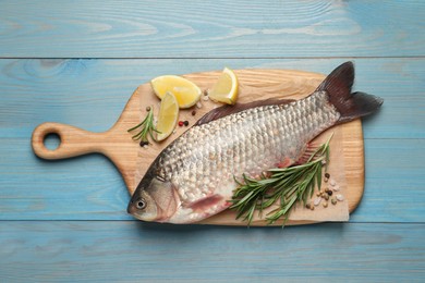 Fresh raw crucian carp and ingredients on light blue wooden table, top view. River fish
