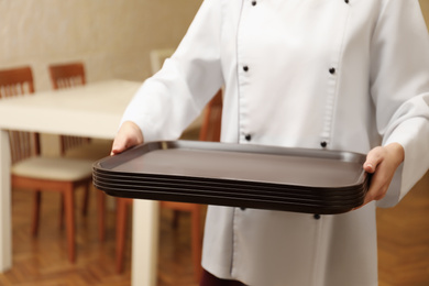 School canteen worker holding plastic trays for food indoors, closeup