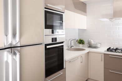 Photo of Modern kitchen interior with combination oven, microwave and fridge