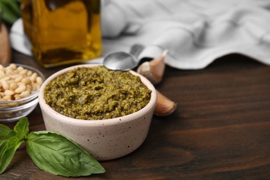 Photo of Tasty pesto sauce and ingredients on wooden table, closeup. Space for text