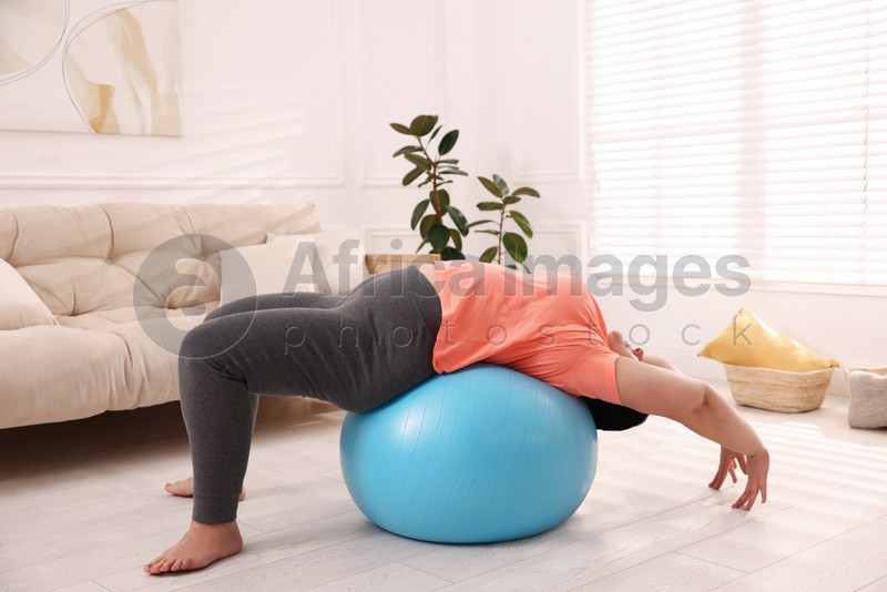 Photo of Overweight mature woman doing exercise with fitness ball at home