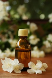 Bottle of jasmine essential oil and beautiful flowers on wooden table